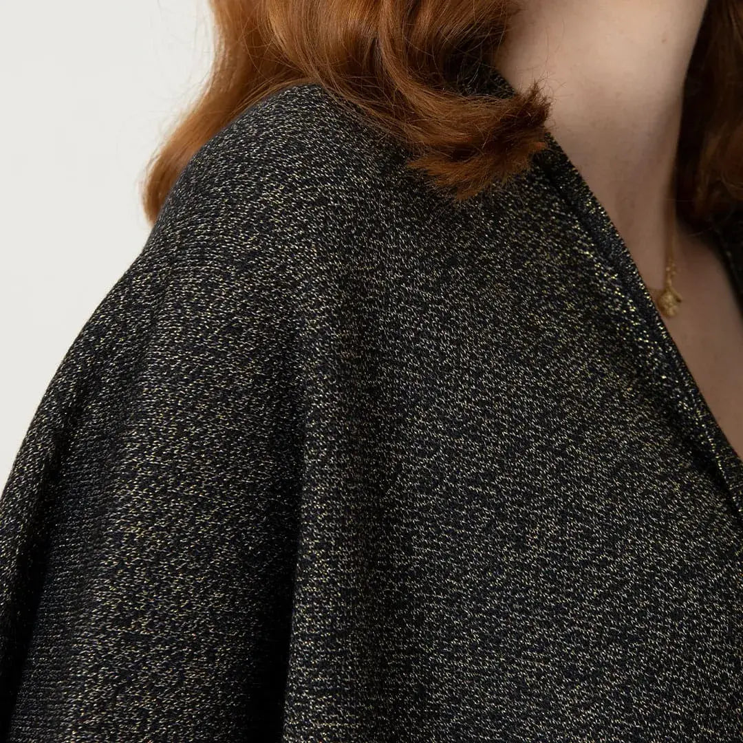Chal Aurora para mujer en tejido de punto negro con destellos dorados de lurex y mangas integradas. Ligero, suave y elegante. Talla única. Hecho en Colombia. Ideal para fiestas de fin de año.