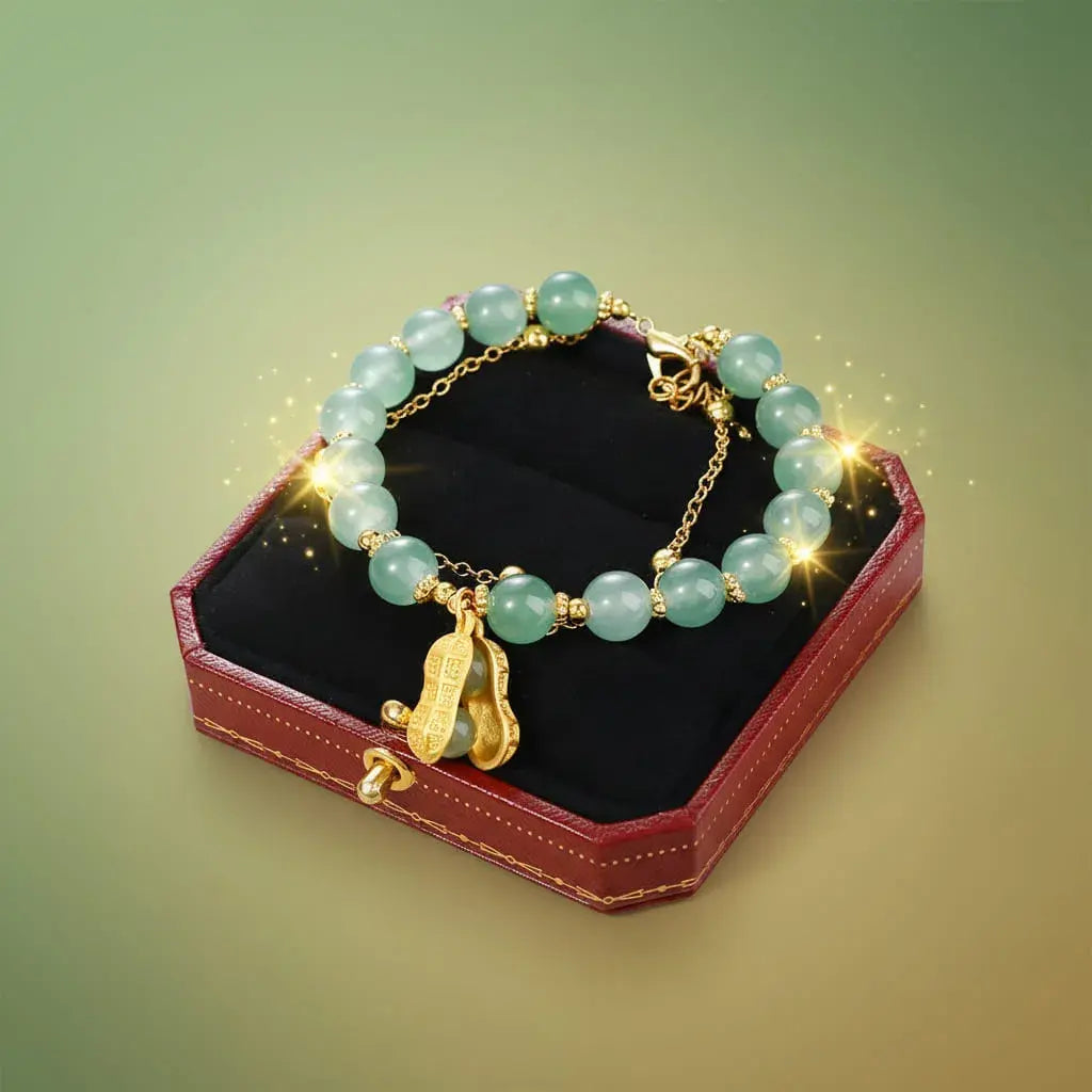 Pulsera de la suerte doble con cuentas verdes estilo jade y dije de maní dorado, símbolo de prosperidad y abundancia en el Feng Shui. Cadena en acero inoxidable, hipoalergénica. 18 cm + 4 cm de extensión.