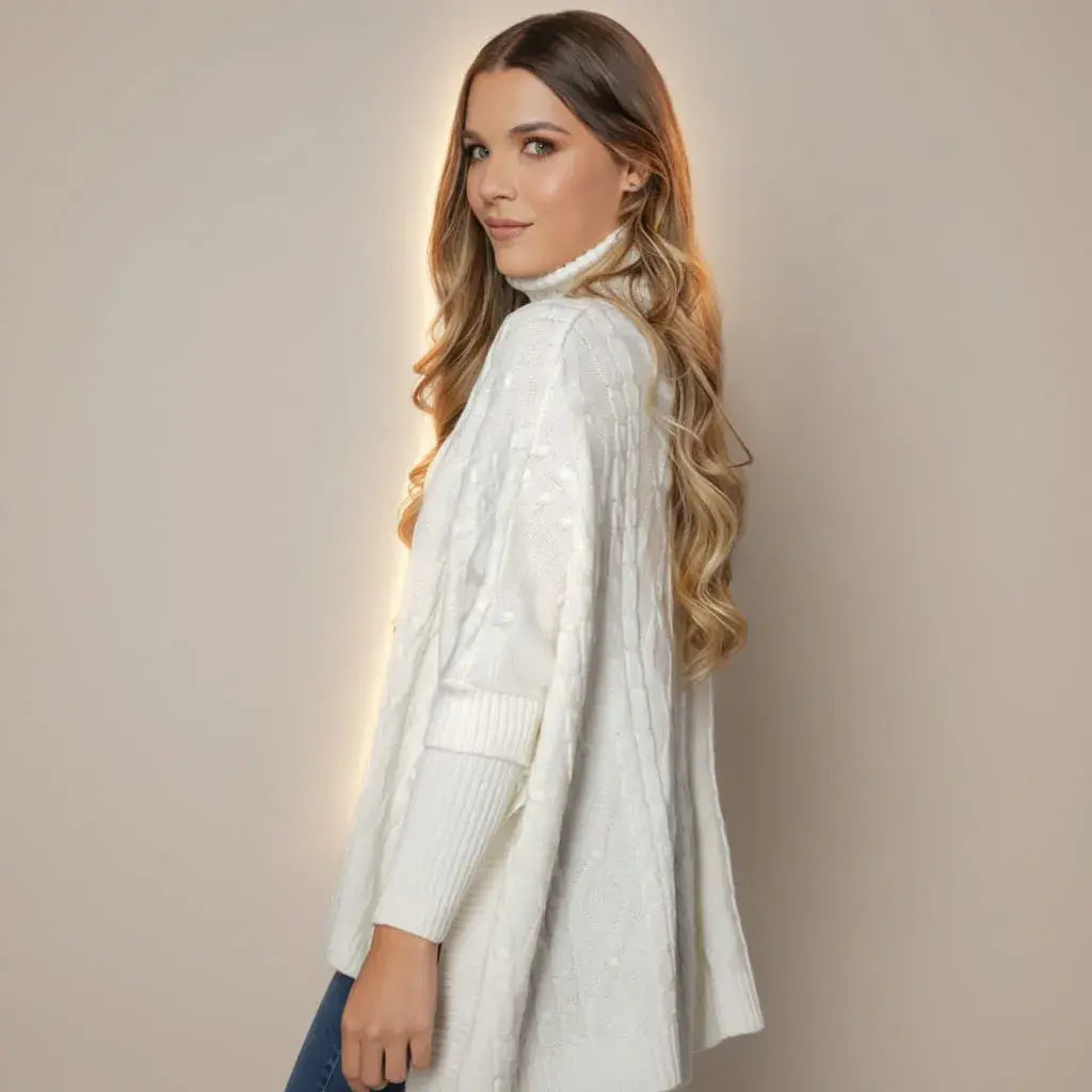 Ruana Roma color marfil para mujer, en tejido de punto suave y cálido. Cuello alto, silueta amplia y fit relajado que favorece a diferentes cuerpos. Abrigo elegante para clima frío.